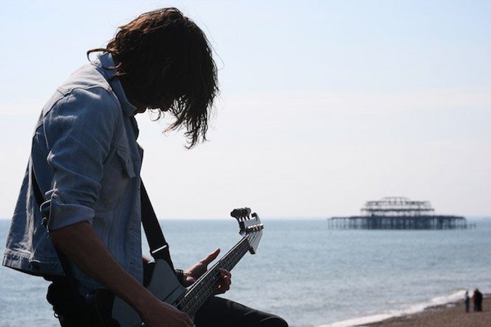 Мужчина, играющий на гитаре у моря, снятый без акцента на баланс в фотографии