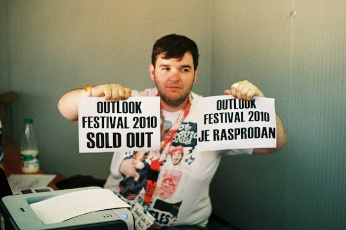 Мужчина держит две печатные таблички с объявлением о том, что фестиваль распродан - баланс фотографии 