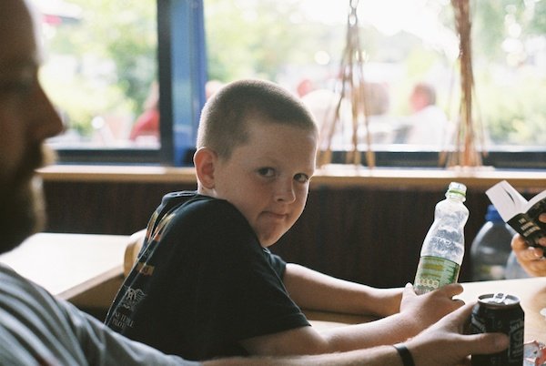 Мальчик, держащий бутылку, смотрит в камеру - оконный свет для портретов