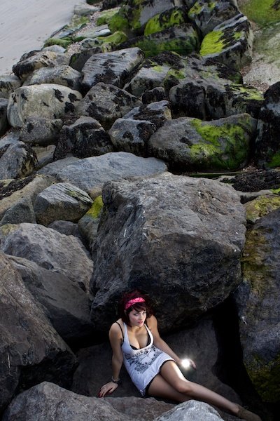 девушка сидит между огромными камнями в нижней части кадра
