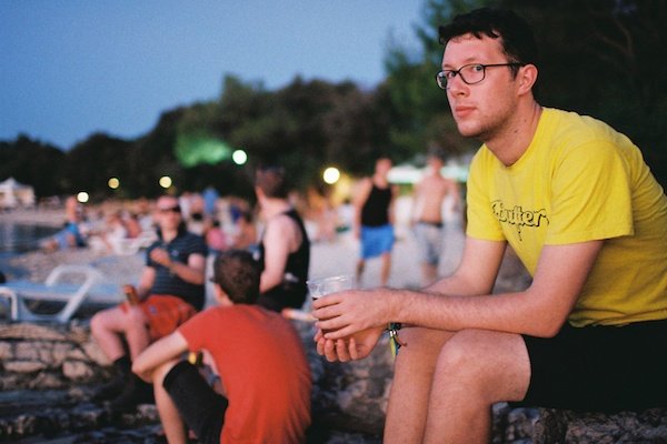Мужчина сидит на пляже с пивом
