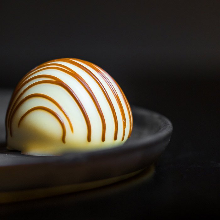 крупный план пищевой фотографии бельгийского белого шоколада, украшенного карамелью.