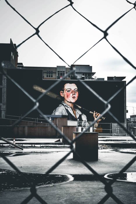 Уличная фотография граффити, снятая через ограду из цепей с объективом 50 мм