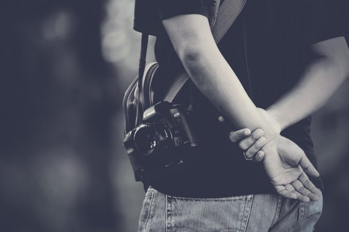 Черно-белый крупный план мужчины с неприметной камерой с объективом 50 мм для съемки откровенных уличных фотографий