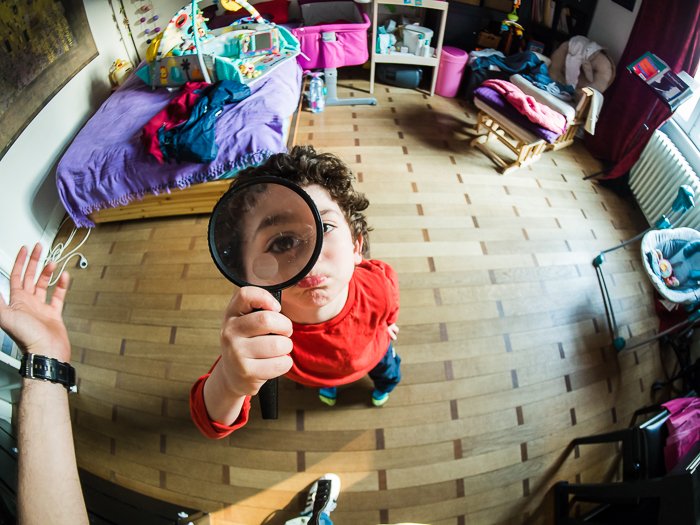 Fisheye lens photo of child holding magnifying glass