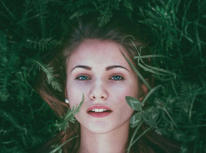 Портретная фотография рыжеволосой женщины, лежащей в траве