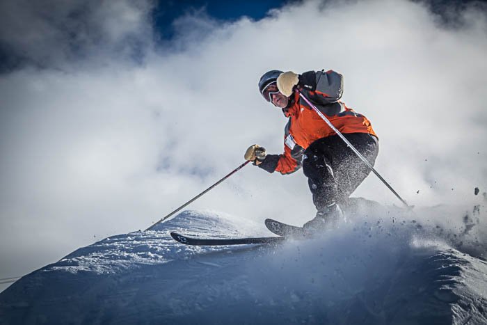 Изображение лыжника, совершающего поворот, с летящим повсюду порошкообразным снегом.