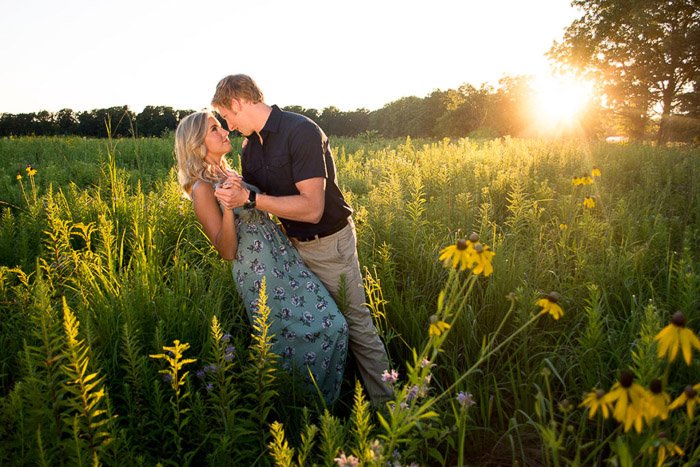 Мужчина сметает с ног свою девушку в освещенном золотым часом поле в спокойной сельской местности