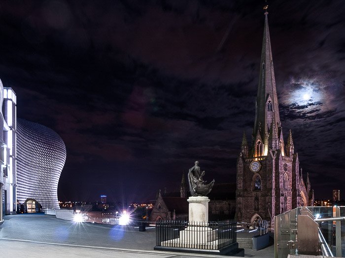 Фотография луны в ночном облачном небе над собором Святого Мартина в Бирмингеме