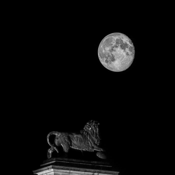 Мощное изображение полной луны над статуей льва