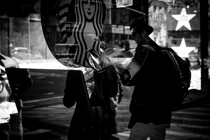 Черно-белая фотография кафе Starbucks с парой, наложенной на клиента внутри. Отражение эффекта двойной экспозиции.