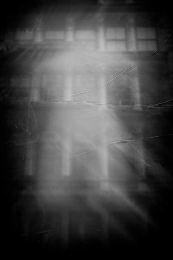 Призрачная дымка опускается на окна здания в черно-белой фотографии отражения улицы.