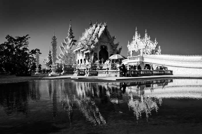 Черно-белая туристическая фотография Белого храма в Чианграе, Таиланд, здание отражается в воде внизу