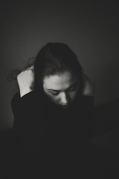 Атмосферный черно-белый портрет молодой женщины, спрятавшей голову в руках. Self portrait photography