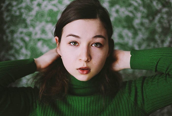 Девушка позирует для автопортретной съемки, подчеркивая использование только одного цвета - зеленого