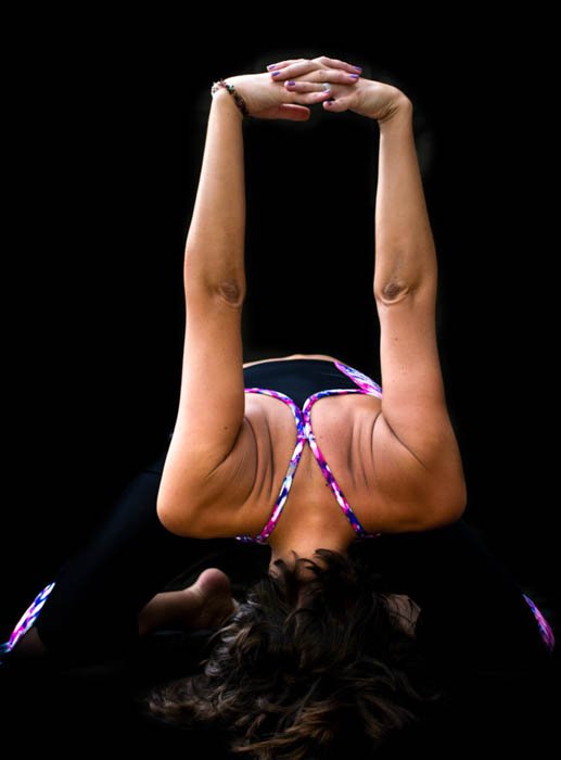 Фотография йогини в позе наклона вперед, демонстрирующая творческое использование черного фона в фотографии