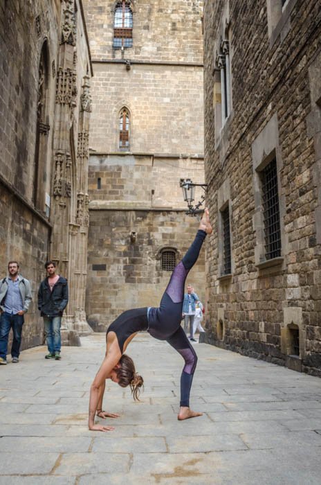 девушка выполняет одноногую позу колеса йоги на улице
