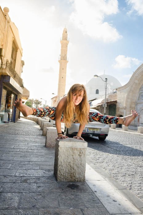 Девушка, выполняющая балансирующую позу йоги на ограждении тротуара