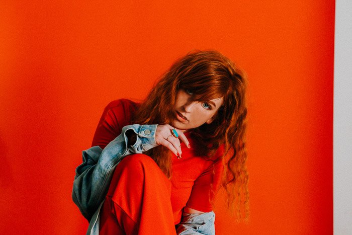 Женщина-модель позирует на фоне ярко-оранжевого фона - работа с фотомоделями