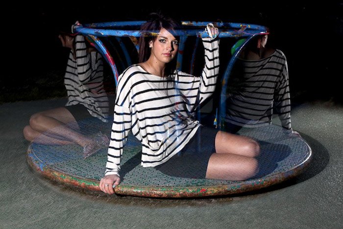 A long exposure night portrait of the female model posing on a merry go round