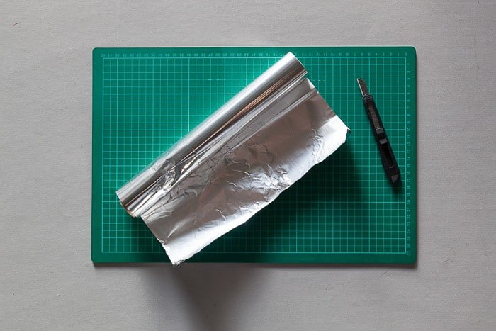 Снимок сверху коврика для резки, рулона фольги и ножа Стэнли - материалов для изготовления лайтбокса для фотографии