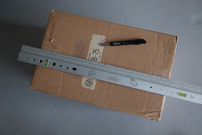 Снимок коробки сверху, стальная линейка и нож - инструменты, необходимые для изготовления светового короба