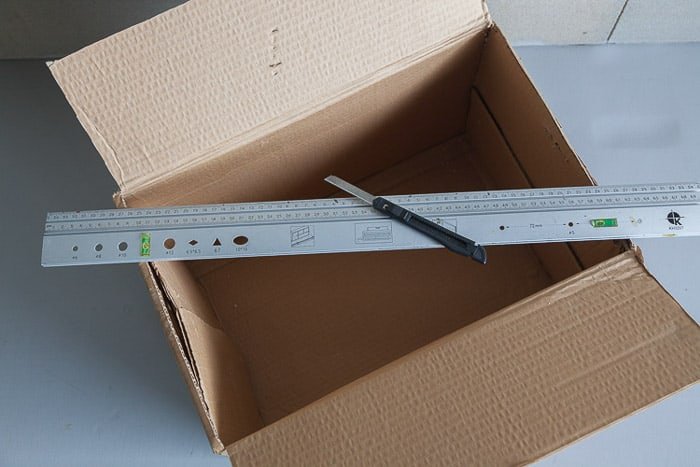 Снимок сверху открытой картонной коробки и других инструментов, необходимых для создания собственного фотолайтбокса
