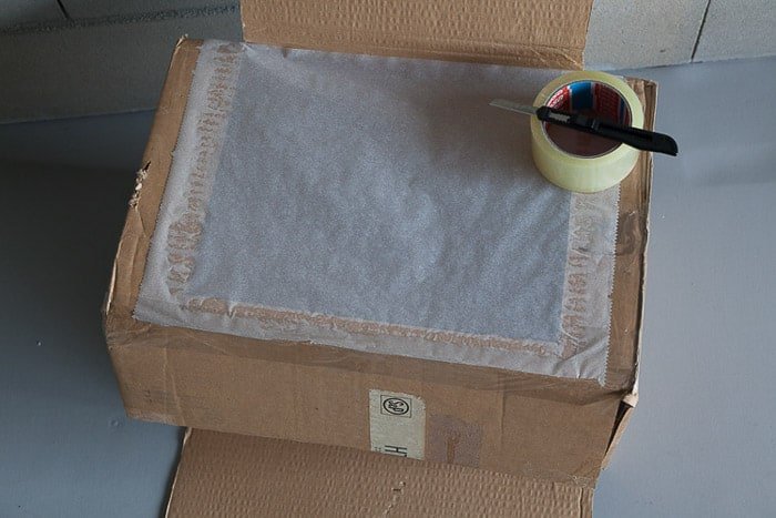 Overhead shot of the open cardboard box and other tools you need to make a diy light box photography