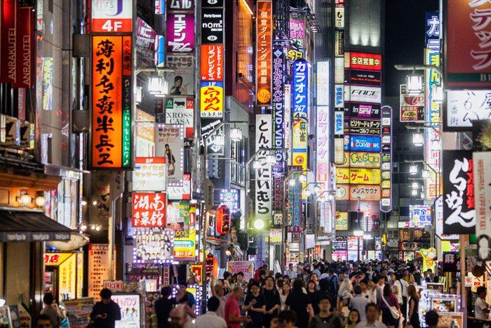 Уличная фотография с неоновой рекламой, сделанная в ночном Токио