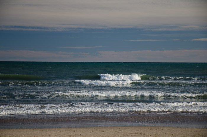 Фотография волн на берегу моря, сделанная с использованием поляризационного фильтра. 