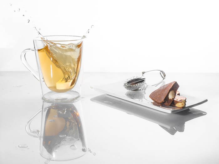 Минималистичная фотография еды, на которой чашка чая плещется рядом с шоколадными конфетами