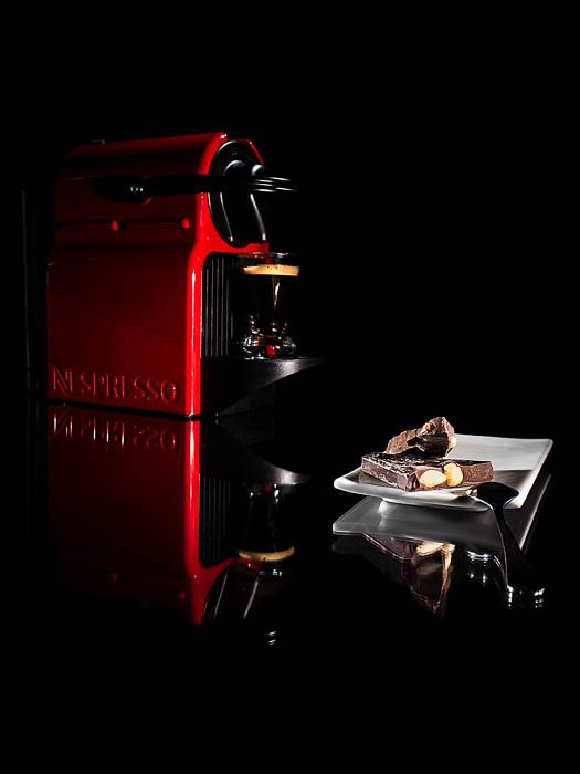 Фотография кофемашины Nespresso в коммерческом стиле рядом с небольшой тарелкой шоколадных конфет