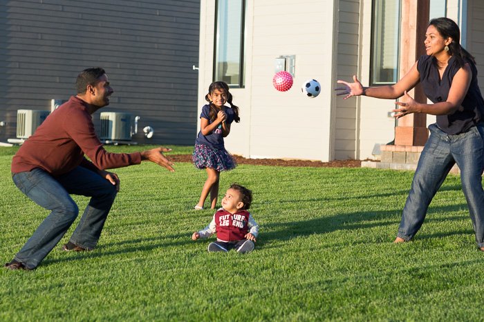откровенный портрет отца и матери, играющих в мяч с двумя маленькими детьми в саду
