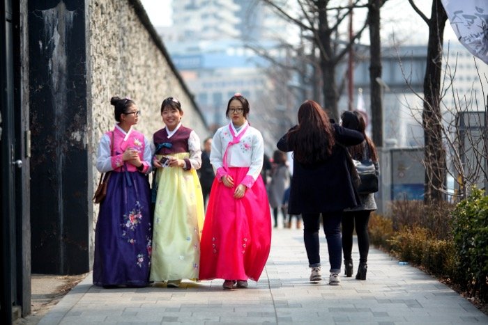 Уличная фотография трех южнокорейских девушек в традиционной одежде, известной как ханбок