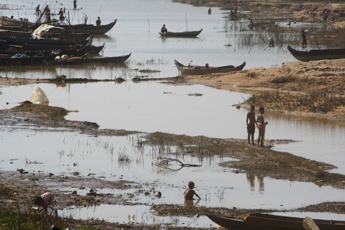 Туристическая фотография, показывающая людей, живущих в крайней бедности. Речная сцена с деревянными рыбацкими лодками и людьми