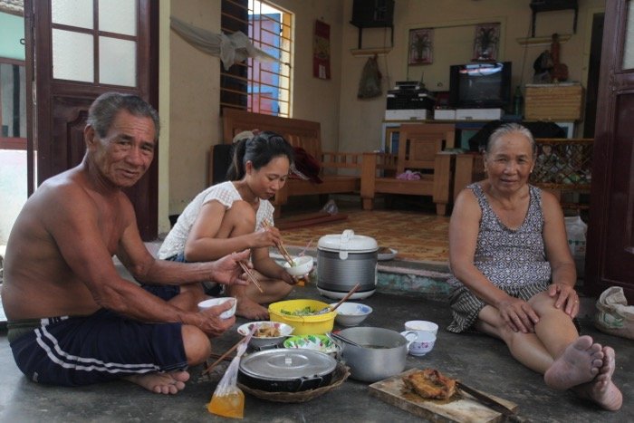 Вьетнамская семья обедает на полу в интерьере своего дома.
