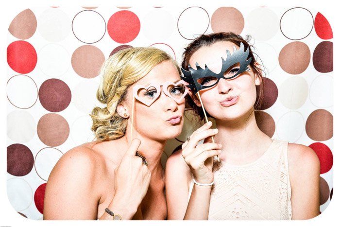две молодые девушки позируют с масками на фоне красочной фотографии