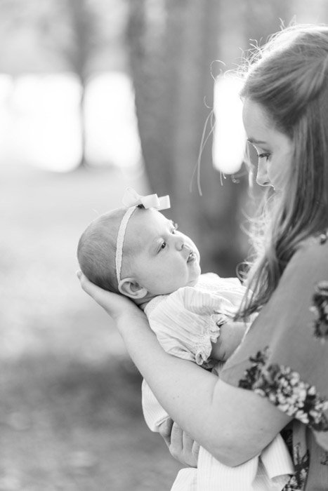 Черно-белая фотография новорожденного, на которой женщина держит ребенка