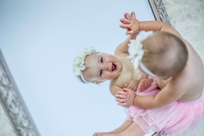 A cute newborn portrait of a baby looking in the mirror