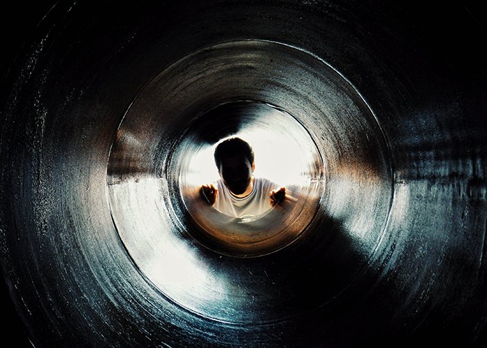 Безликий портрет человека, смотрящего вверх через темный туннель