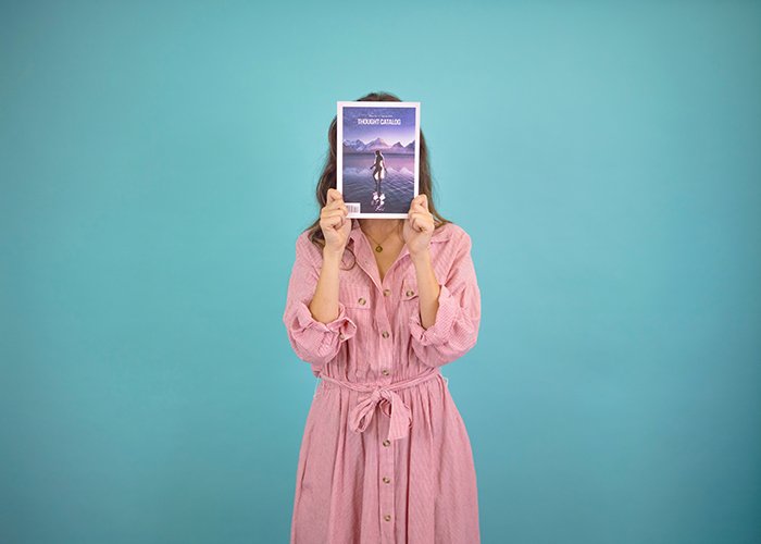 Женщина в розовом использует журнал для создания безликого портрета для рекламы своего бизнеса
