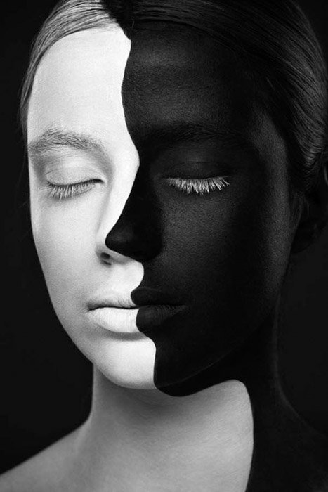 Портрет женского лица, раскрашенного наполовину в черный и наполовину в белый цвет на черном фоне, как пример сопоставления цветов.
