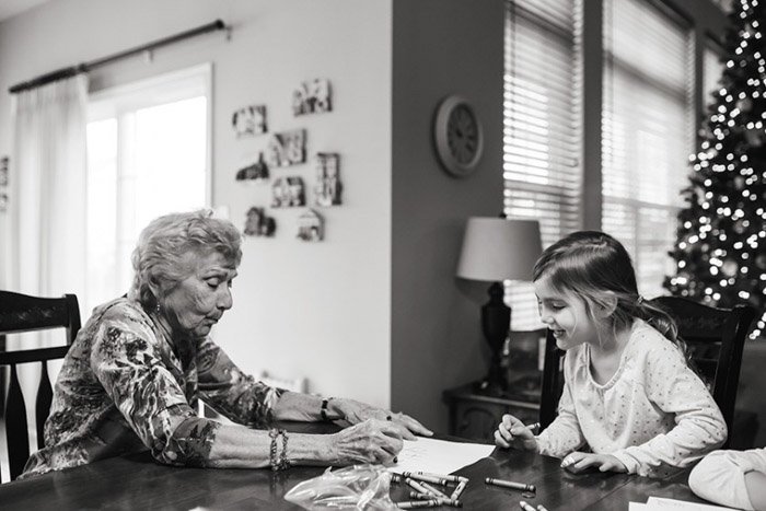 Черно-белая фотография бабушки и ребенка за столом, раскрашивающих книгу