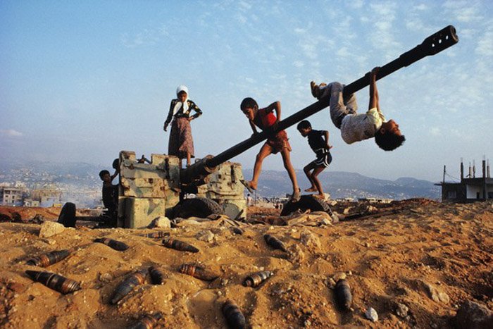 Документальная фотография детей, играющих вокруг заброшенного артиллерийского орудия.