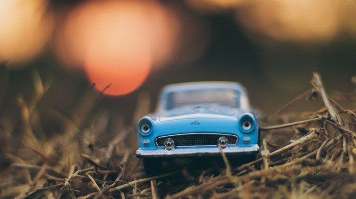 Фотография игрушечной синей машинки на траве