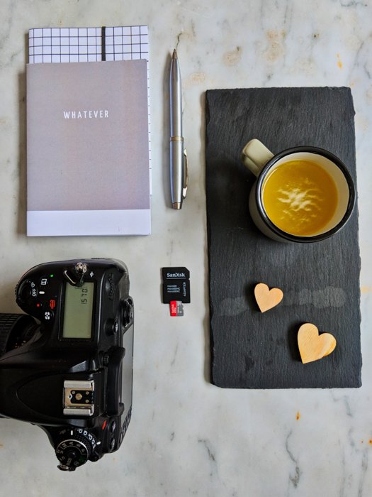 Фотоснимок натюрморта с фотоаппаратом, блокнотом, ручкой, чашкой кофе и картой памяти