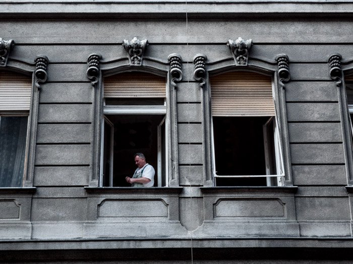 Уличная фотография открытых окон здания, человек стоит внутри одного из них, сделанная на камеру Panasonic gh5 Крейгом Халлом