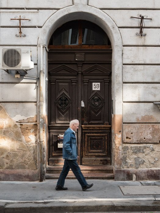 Уличная фотография человека, проходящего мимо дверного проема в Будапеште, сделанная на камеру Panasonic gh5 Крейгом Халлом