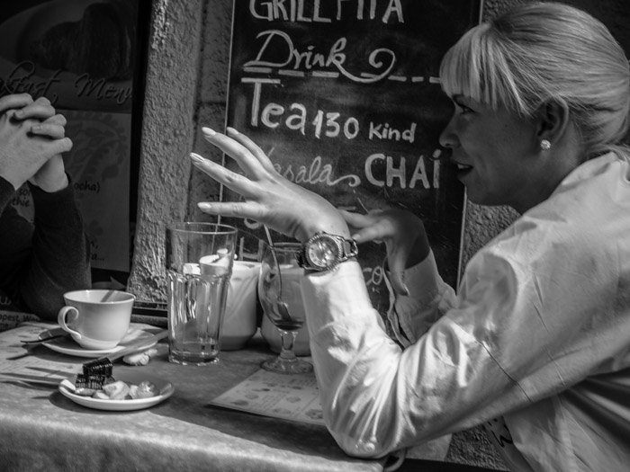 Черно-белая уличная фотография людей, беседующих за столиком кафе, сделанная на Panasonic gh5 Крейгом Халлом