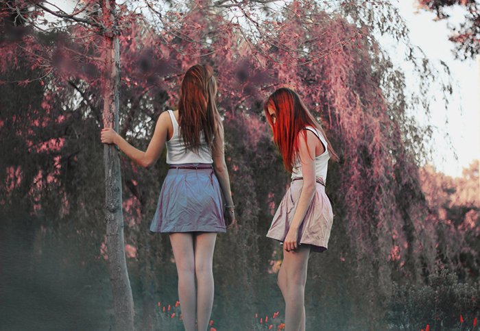 Мечтательный портрет двух девушек на размытом фоне леса. 